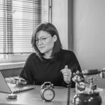 A businesswoman using a laptop at her desk with a vintage phone and an alarm clock, creating a mix of modern and retro vibes.