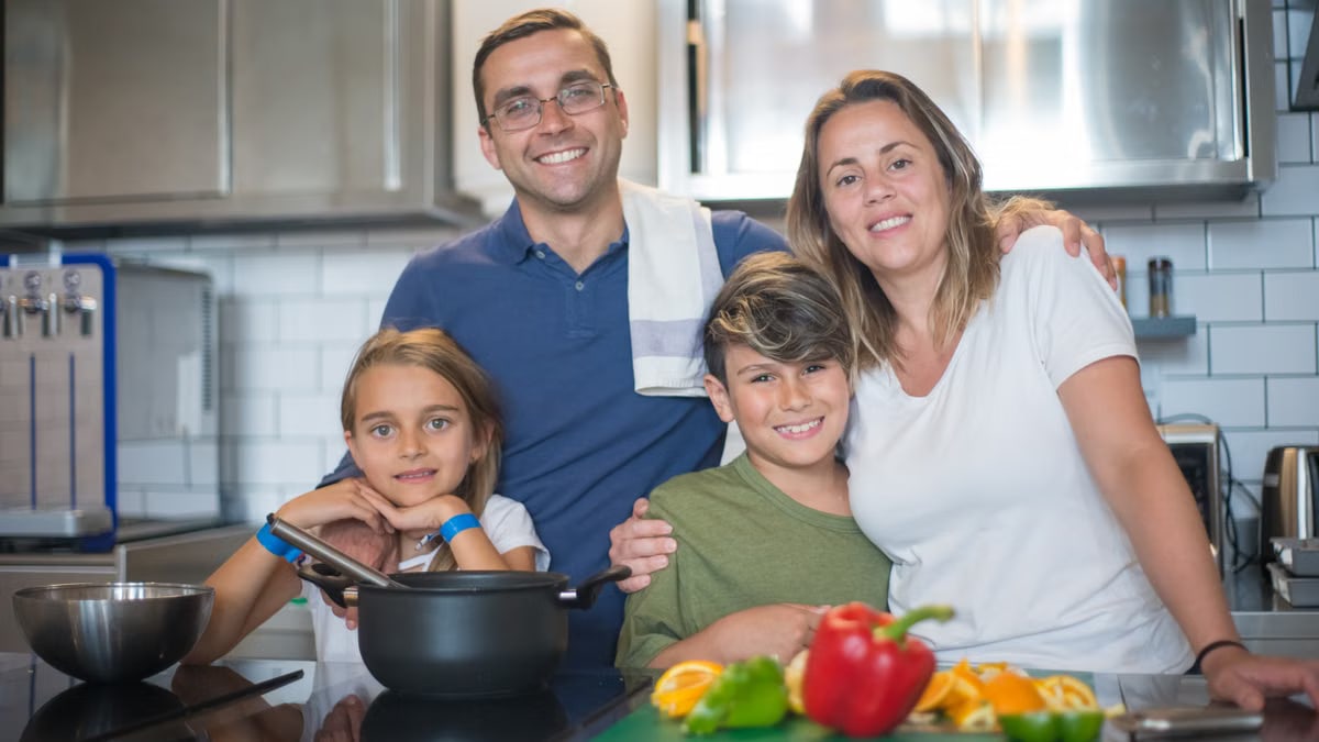 A joyful family of four cooking together in a modern kitchen, highlighting family bonding and culinary activities.